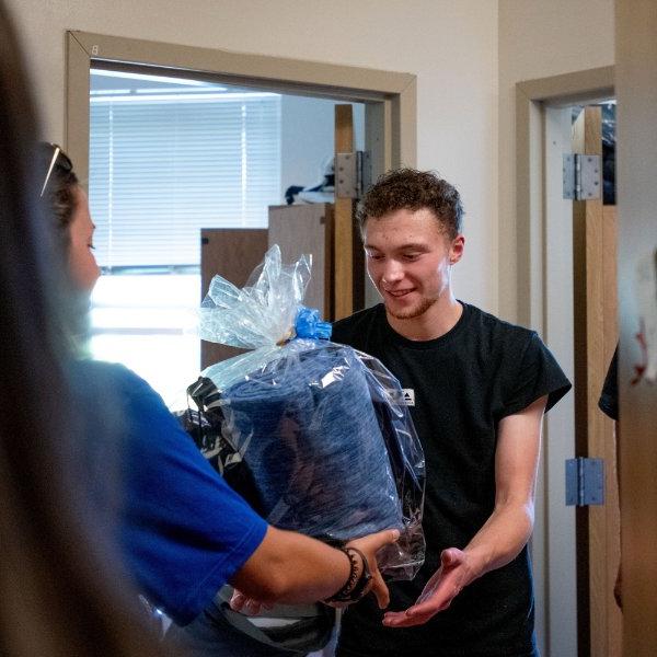 Connor Pung holds a gift basket being presented to him during his move-in.